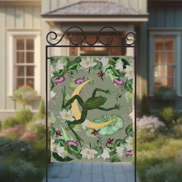 a green frog on a green background with white flowers and a house in the background