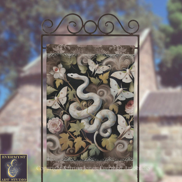 a decorative banner with a snake and butterflies on a metal frame, set against a blurred background of trees and a building.