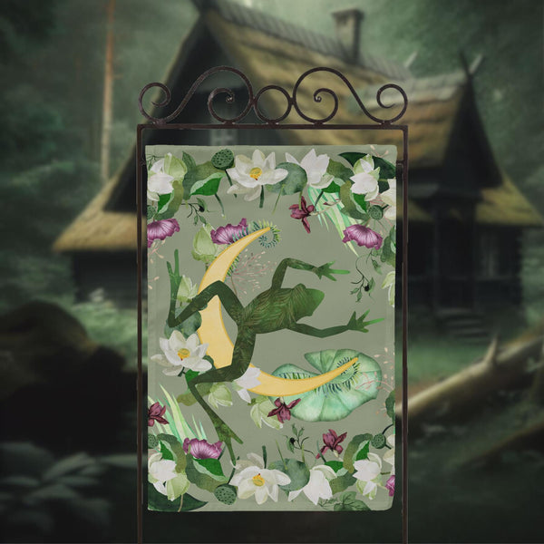 a picture of a frog with flowers and a house in the background