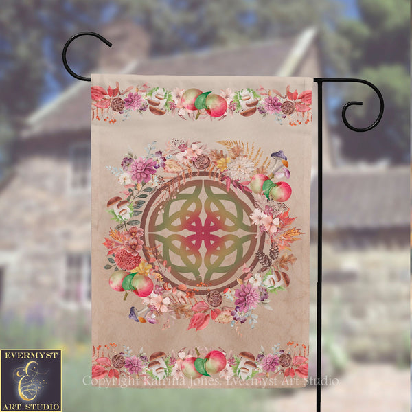 A banner with a circular design featuring a Celtic knot surrounded by various colorful flowers and fruits, such as apples and pears, hanging on a metal hook.